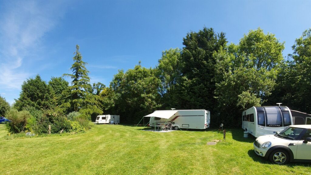 Spacious grass touring pitches surrounded by trees at Brooklands